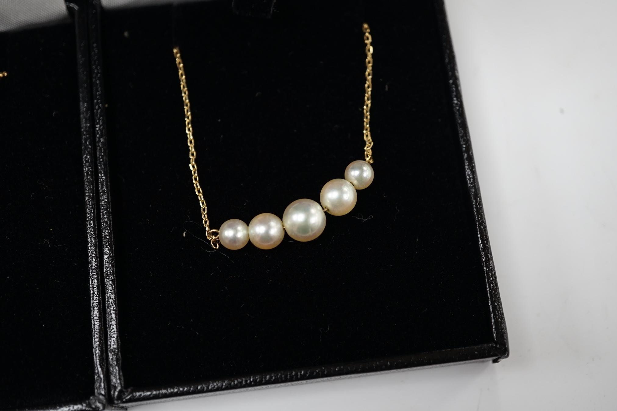 A modern 18k and two stone cultured pearl set pendant necklace, with diamond chip set collars, 42cm, gross weight 5.9 grams, together with a 14l and five stone cultured pearl set necklace, 35cm, gross weight 3 grams. Con
